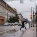 Pedestrian crosses street on rainy day at bus stop